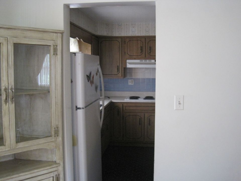Kitchen with wood cabinets, white refrigerator, and a light-colored hutch
