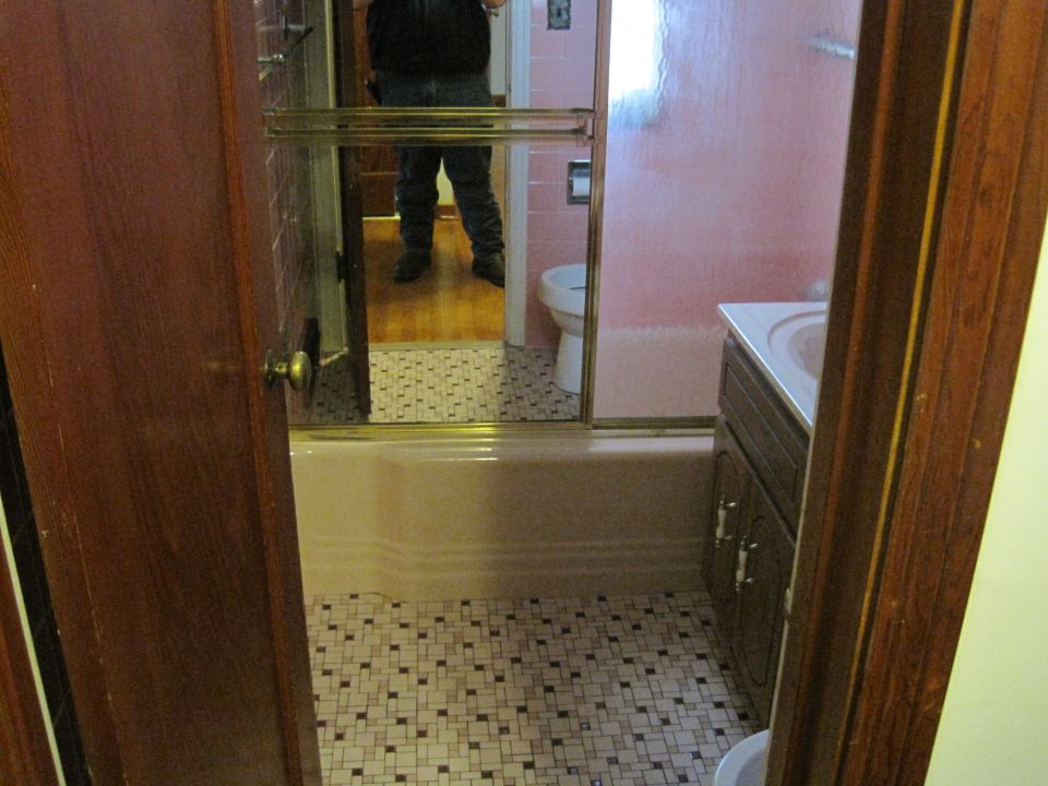 Bathroom with pink tub, toilet, and vanity, reflected in a mirror
