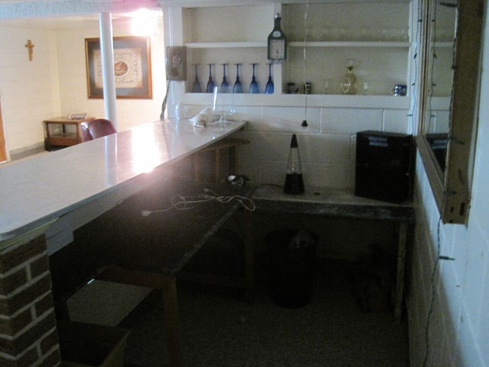 Bar area with a white countertop, brick pillar, and shelves with blue glasses
