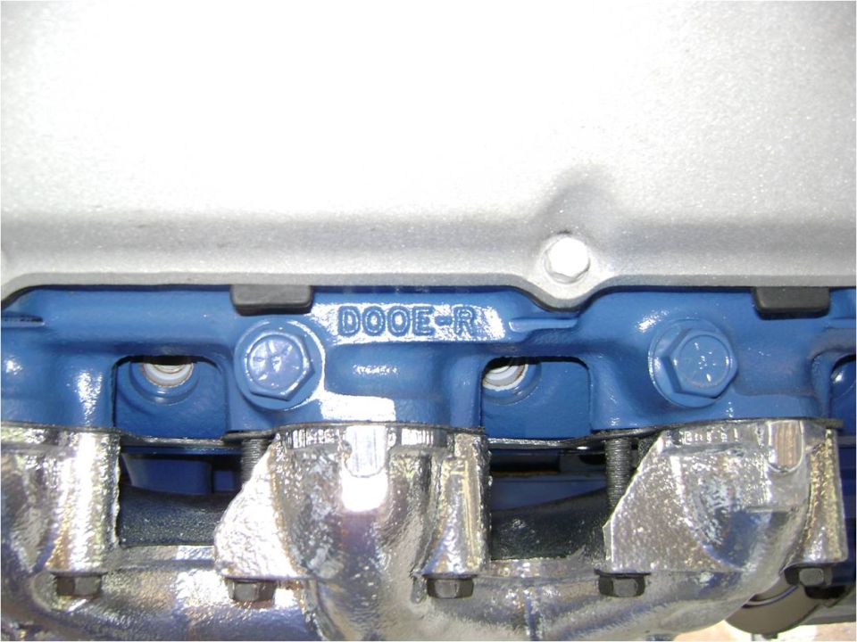 Close-up of D0OE-R casting mark on a blue Ford cylinder head above a polished exhaust manifold