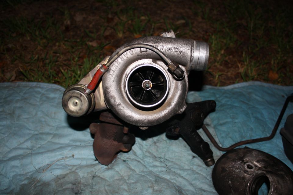 Garrett turbocharger with red and black hoses attached, sitting on a blue cloth outdoors