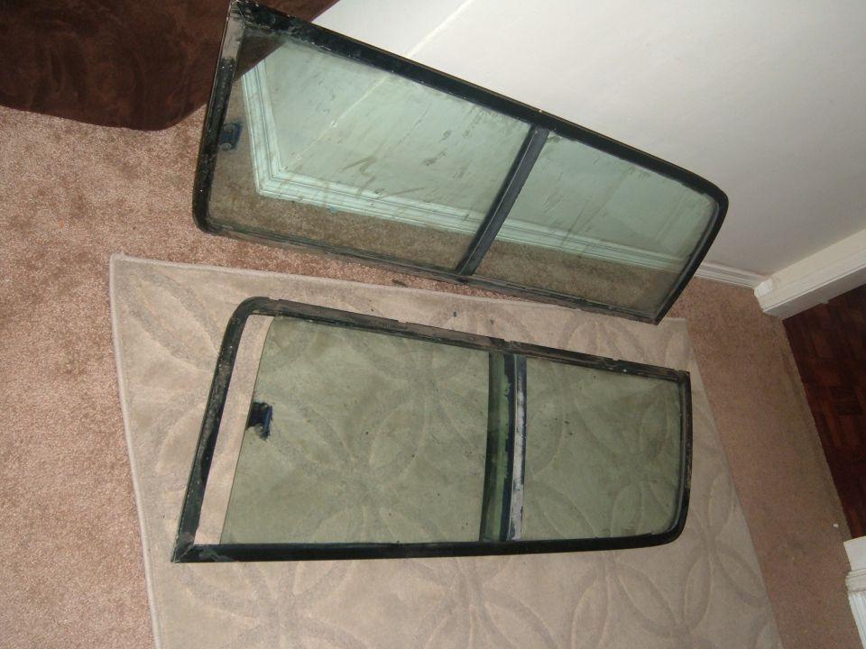 Pair of removed door window frames with glass standing on carpet indoors