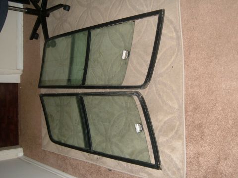 1988 Ford Bronco - Two removed door glass assemblies with black window frames, sliding vent dividers and chrome latch handles, laid out on a patterned rug and…