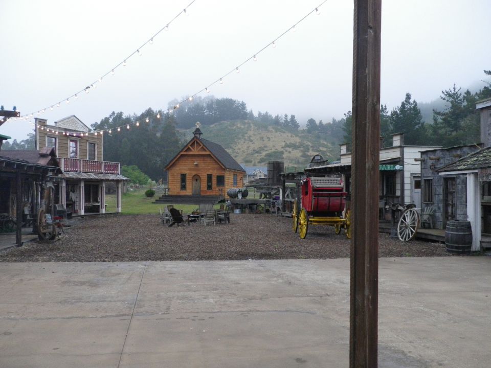 Western town with wooden buildings, a church, and a horse-drawn carriage