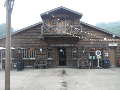 1991 Ford Bronco - A rustic wooden building, possibly a ranch or farm, is decorated with string lights and features old wagon wheels as benches.