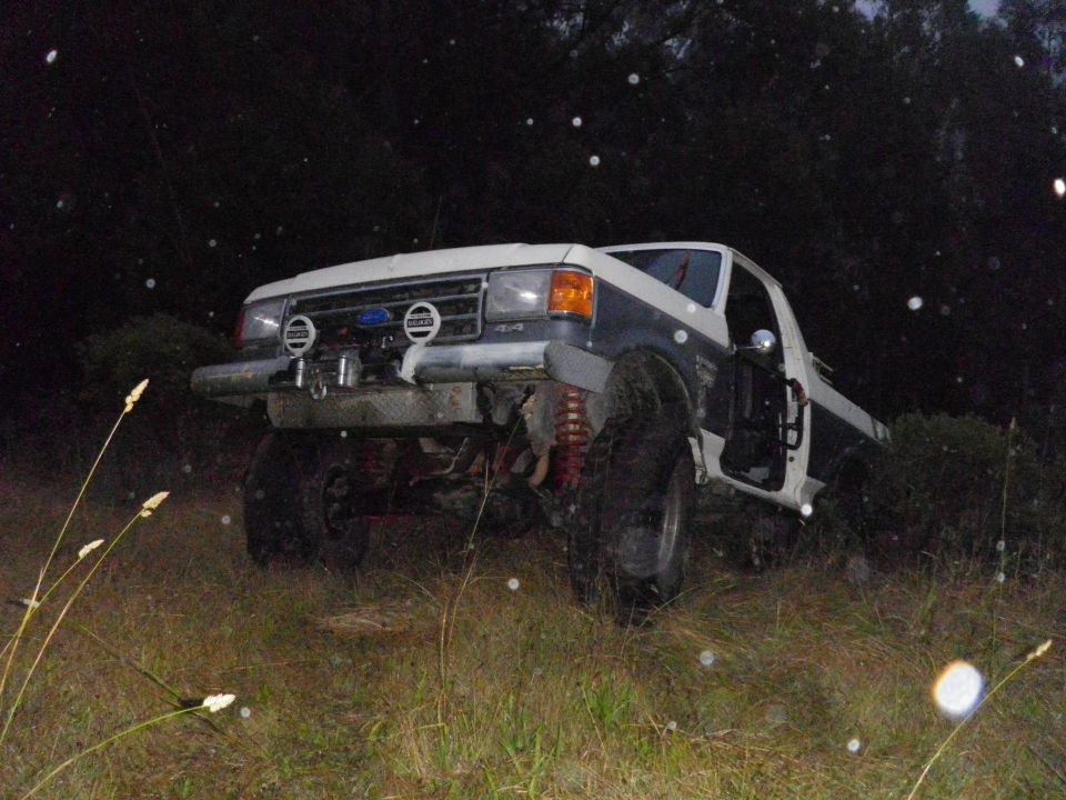 White and blue lifted truck with off-road tires, 3q-front view. 1991 Ford Bronco