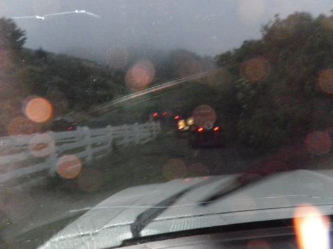 1991 Ford Bronco - View from inside a vehicle looking through the windshield at a road with a white fence and other vehicles in the distance.