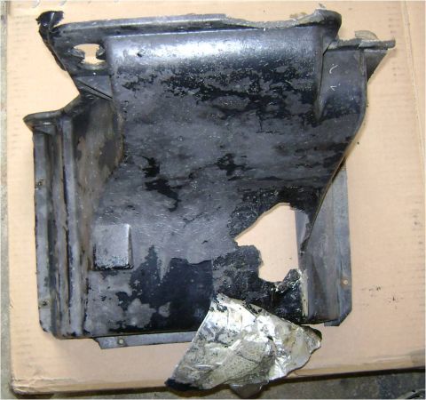 1972 Ford Ranchero - This is a damaged plastic part, possibly from a vehicle's undercarriage, with a large hole and detached foil.
