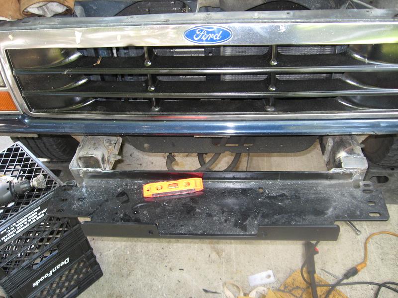 Front grille and bumper of a Ford truck, possibly a Bronco or F-series, with a level on the bumper