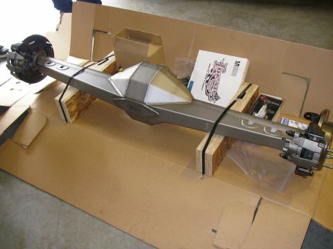 1990 Ford Bronco - freshly built rear axle housing with disc brakes and gusseted truss sitting on wood blocks atop cardboard.
