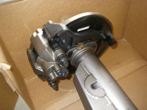 1990 Ford Bronco - Rear disc brake conversion mounted on the end of a fabricated axle housing tube: a cast caliper with bleeder screw and pad hardware clamps…