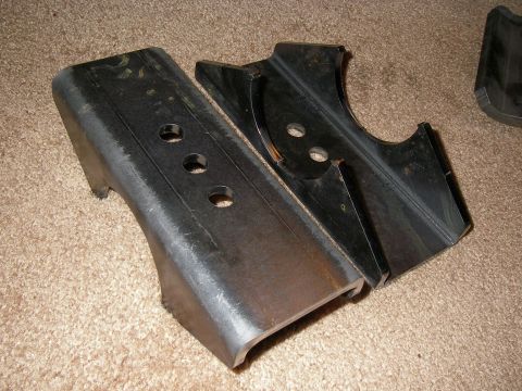 1990 Ford Bronco - Two metal brackets, likely automotive parts, are shown on a carpeted floor.