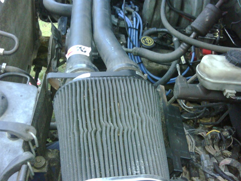 Engine bay of a 1991 Ford Bronco showing a large, dirty air filter and blue spark plug wires