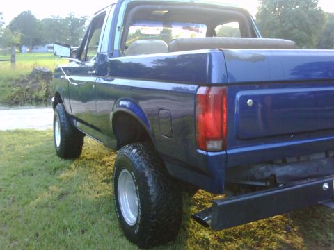 1991 Ford Bronco - This blue Ford Bronco is shown from the rear quarter angle with the top removed.