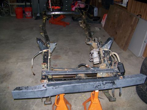 1992 Jeep YJ - The frame of a Jeep is shown on jack stands, with a front bumper and some attached components visible.