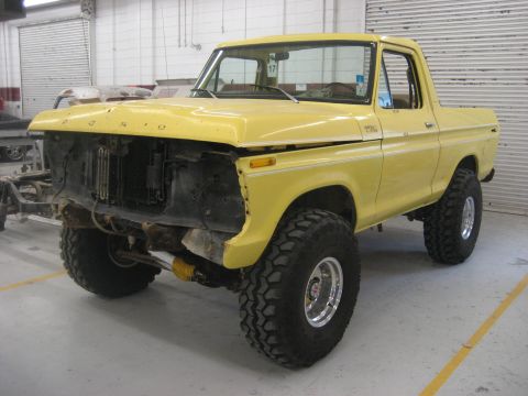 1978 Ford Bronco - A yellow 1978 Ford Bronco is shown with its front grille and bumper removed, sitting on large off-road tires.