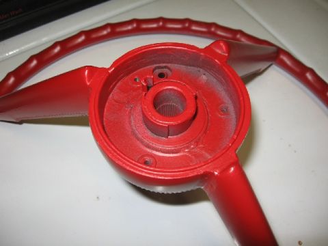 1966 Ford F-100 - Close-up of a red steering wheel component, revealing the central hub and spokes with a splined shaft opening.