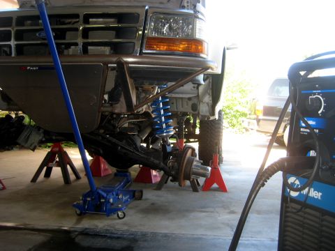 1996 Ford Bronco - Front suspension of a Ford truck, likely from the early to mid-1990s, undergoing maintenance.