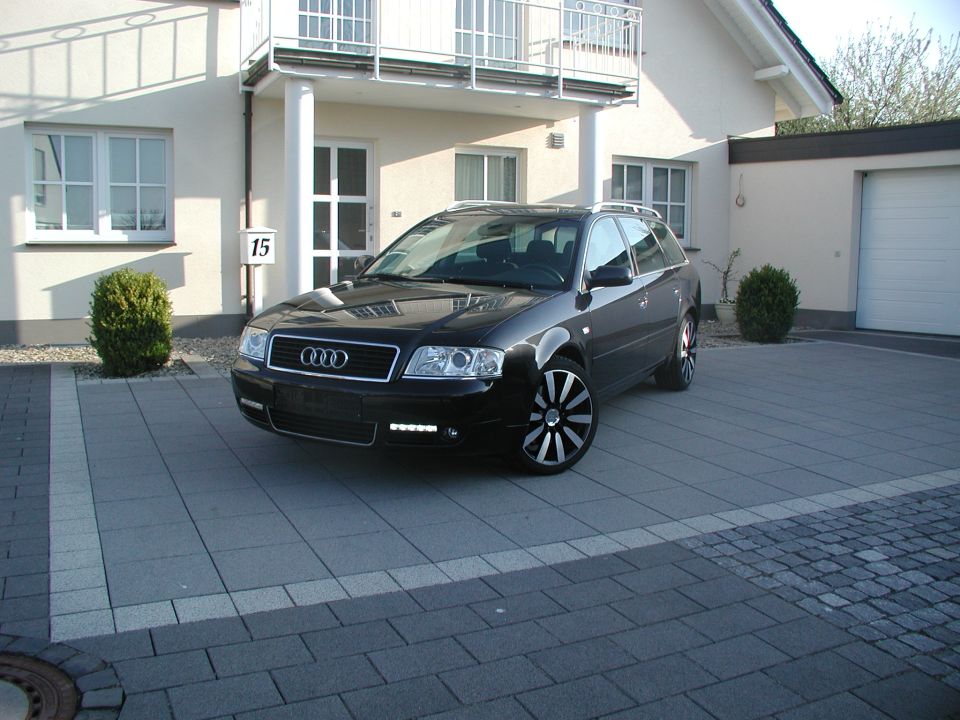 Black Audi A6 Avant wagon parked in driveway, 3/4 front view