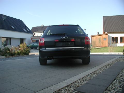 2003 Audi A6 - A black Audi A6 station wagon is parked in a driveway, with houses and a green car in the background.