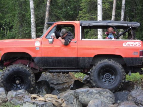 1990 Chevrolet Suburban - This modified SUV is navigating a rocky trail with a driver and a doll in the passenger seat.