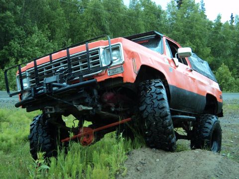 1990 Chevrolet Suburban - This heavily modified truck features a prominent brush guard and oversized tires, suggesting off-road use.