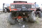 1990 Chevrolet Suburban - Modified truck with large off-road tires and a prominent grille, parked outdoors with other vehicles nearby.