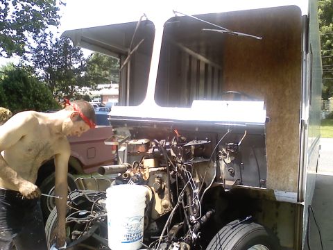 1990 Ford Bronco - A man works on a vehicle's engine, with another truck in the background.