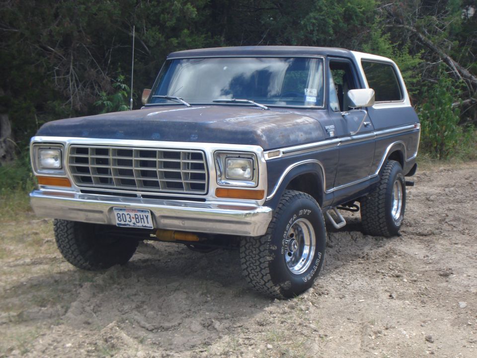 Dark blue and white 1978 Ford Bronco with chrome grille and bumper, parked on dirt