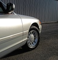 2000 Ford Crown Victoria - A silver 2000 Ford Crown Victoria is viewed from the side, showing its front wheel and part of the body.