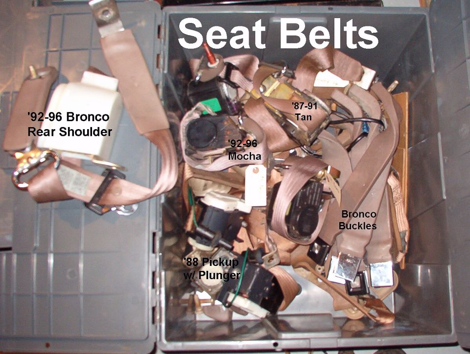 Bin of assorted tan and brown Bronco seat belts labeled by year and type