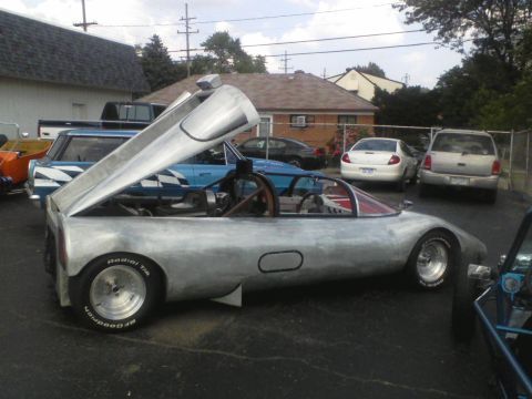 1960 Ford Falcon - A custom-built aluminum sports car is parked outdoors with its hood open, revealing the engine bay.