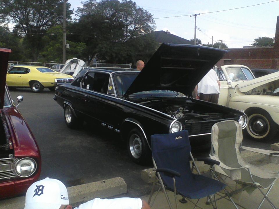 Black 1963 Dodge Dart with hood open, parked next to a yellow car and a tan car