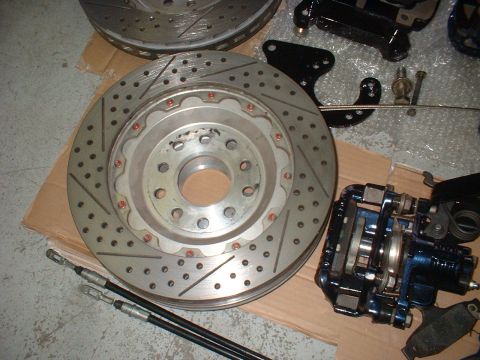 1969 Ford Torino - Performance brake components, including a drilled and slotted rotor and a blue caliper, are laid out on cardboard.