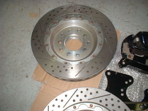 1969 Ford Torino - Close-up of slotted and drilled brake rotors and a caliper bracket, with "SUPERMOTORS.NET" visible on the lower rotor.