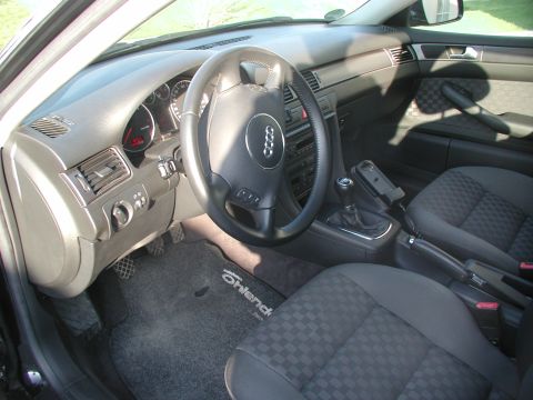 2003 Audi A6 - The interior of a car shows the dashboard, steering wheel, and front seats. A phone mount is attached to the center console.