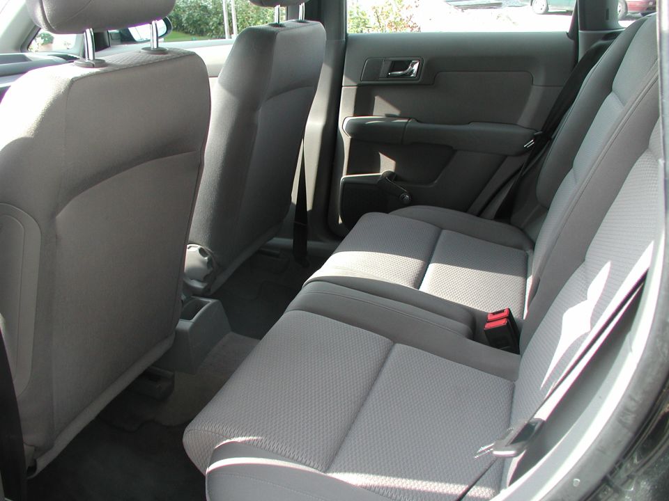 Car interior with gray fabric seats and door panels, viewed from the rear passenger side
