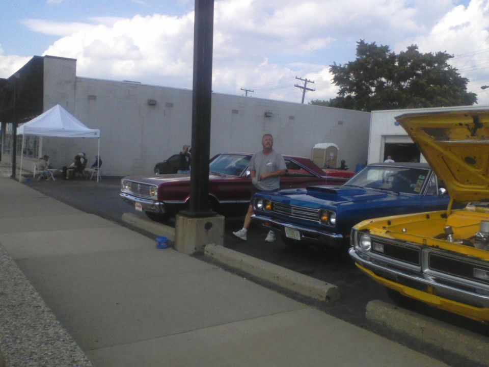Blue 1969 Plymouth Road Runner parked next to a yellow car with hood open and a red car behind it