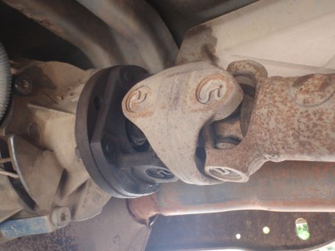 1994 Ford Bronco - Underside view of a vehicle's drivetrain, focusing on the driveshaft and U-joint assembly.