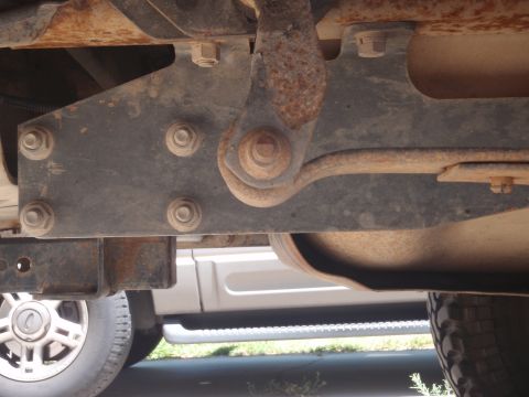 1994 Ford Bronco - Close-up view of the rusty undercarriage of a vehicle, with a portion of another vehicle visible below.