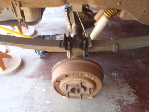 1994 Ford Bronco - Close-up of a vehicle's rear suspension system, showing leaf springs and a drum brake assembly.