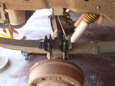 1994 Ford Bronco - Close-up view of the rear axle and leaf spring suspension system on a 1994 Ford Bronco, a yellow-booted shock absorber.