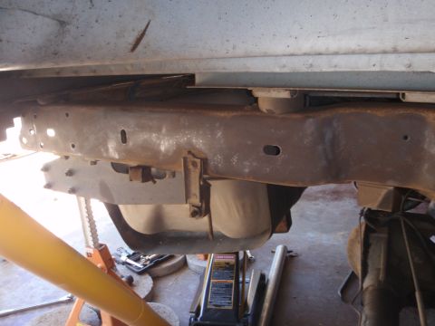 1994 Ford Bronco - Undercarriage view of a vehicle's frame and suspension components, showing signs of rust and repair equipment.