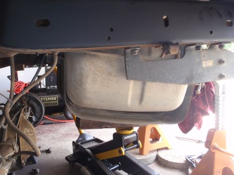 1994 Ford Bronco - Vehicle's fuel tank supported by jack stands during maintenance. Air compressor in background.