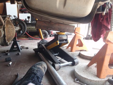 1994 Ford Bronco - A vehicle is suspended by a jack and jack stands in a garage, with tools scattered around.
