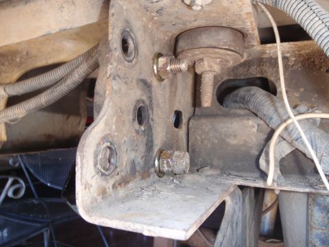 1994 Ford Bronco - This image shows a close-up of a vehicle's undercarriage, focusing on a metal bracket and its associated hardware.