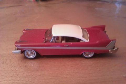 1991 Ford Crown Victoria - A red and white toy car with prominent fins is displayed on a wooden surface.
