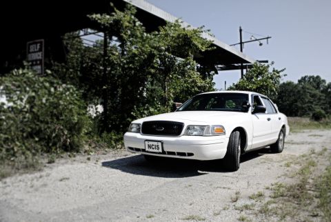 2002 Ford Crown Victoria - White 2002 Ford Crown Victoria parked on gravel, with a building and trees in the background.