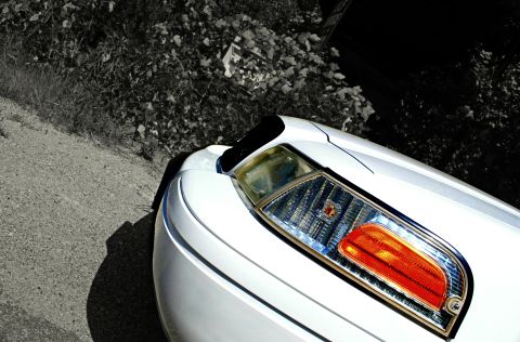 2002 Ford Crown Victoria - The front corner and headlight of a white 2002 Ford Crown Victoria are visible in this close-up shot.