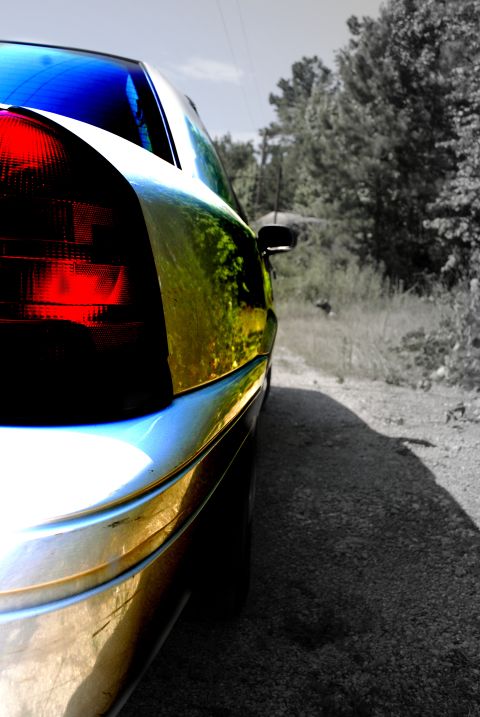 2002 Ford Crown Victoria - Close-up of the rear of a 2002 Ford Crown Victoria on a gravel road with trees in the background.